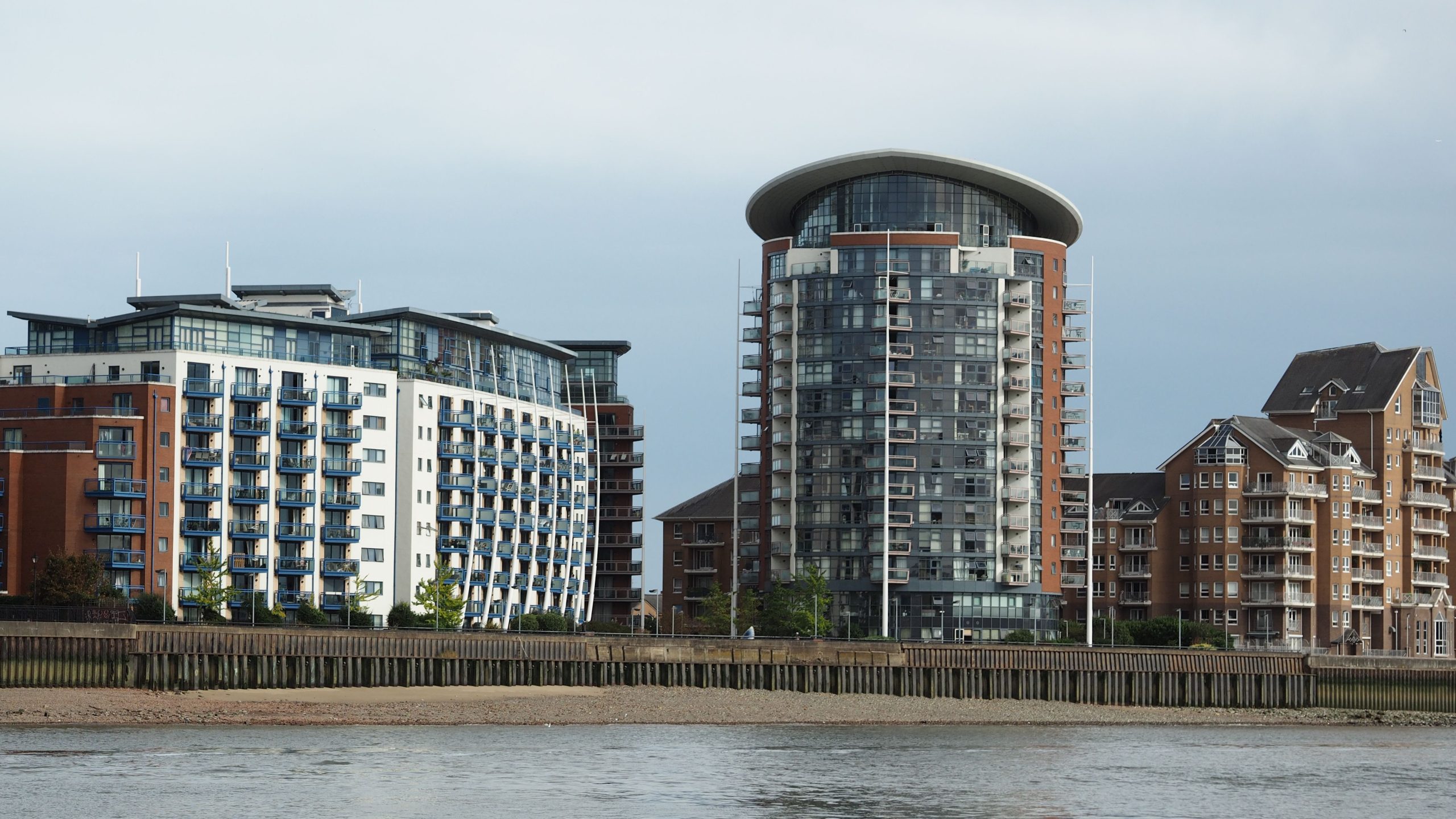 Striking modern riverside apartments showcasing unique architectural styles and glass facades.